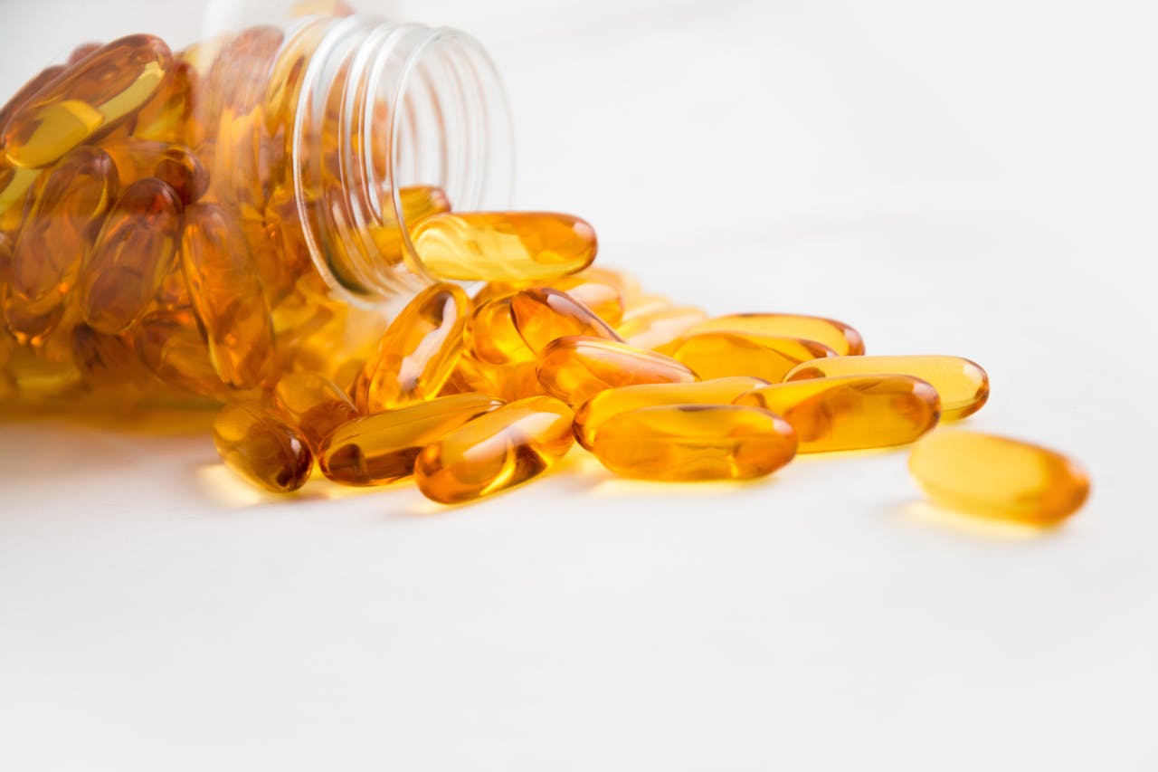 our-experience Close-up of fish oil capsules spilling from a bottle on white background.